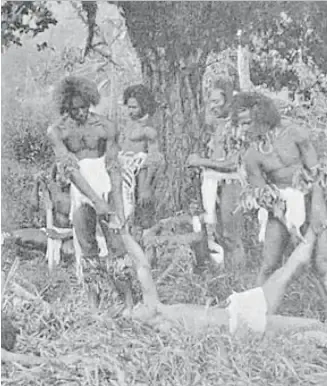 Original: Men of Fiji around a figure lying on the ground — early photograph, probably a staged scene (awaiting cultural review)